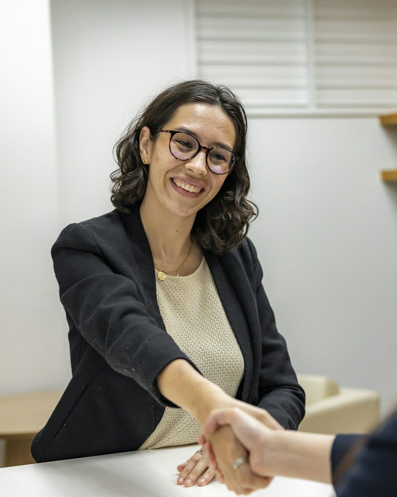 Smiling HR manager shaking hands with a new hire across a desk