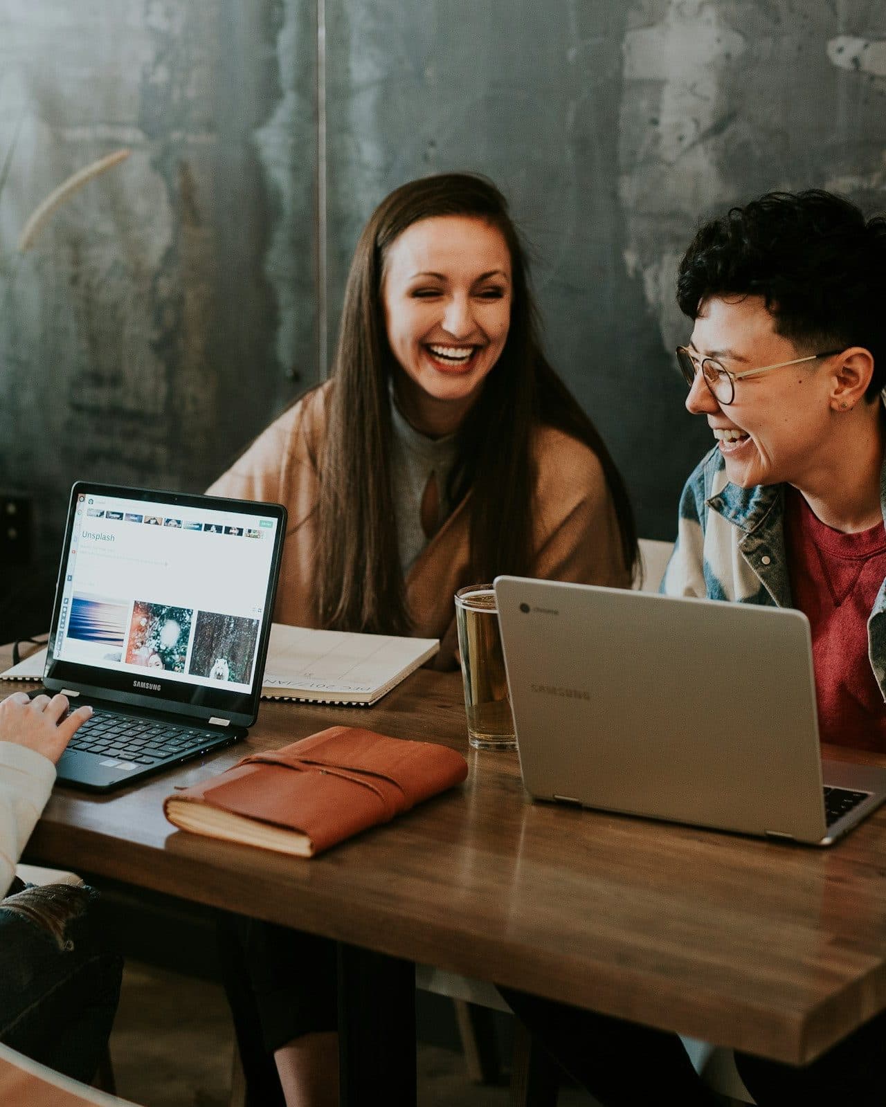 Young professionals learning together and laughing over laptops at a shared table