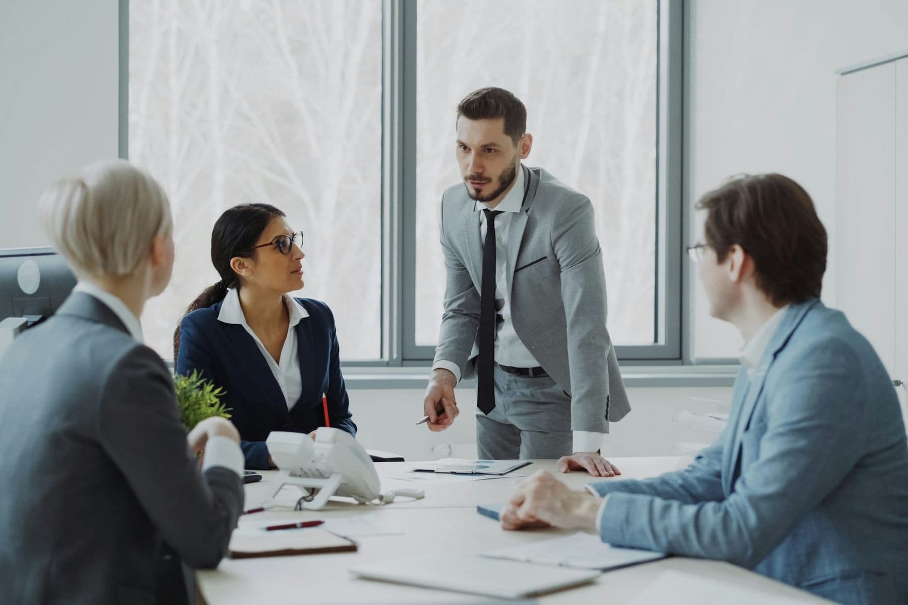 Senior leaders in suits discussing strategy around a boardroom table