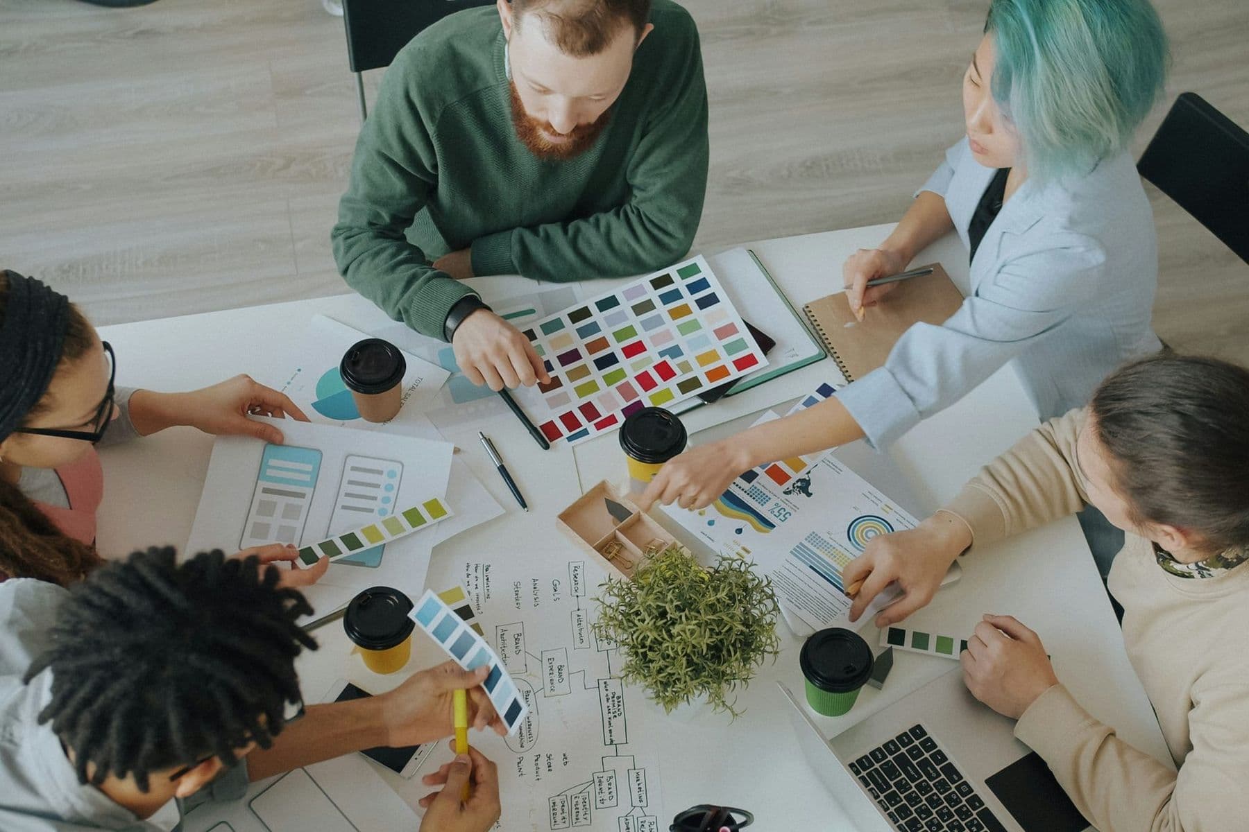 Overhead view of a creative marketing team working with colour swatches, layouts and charts