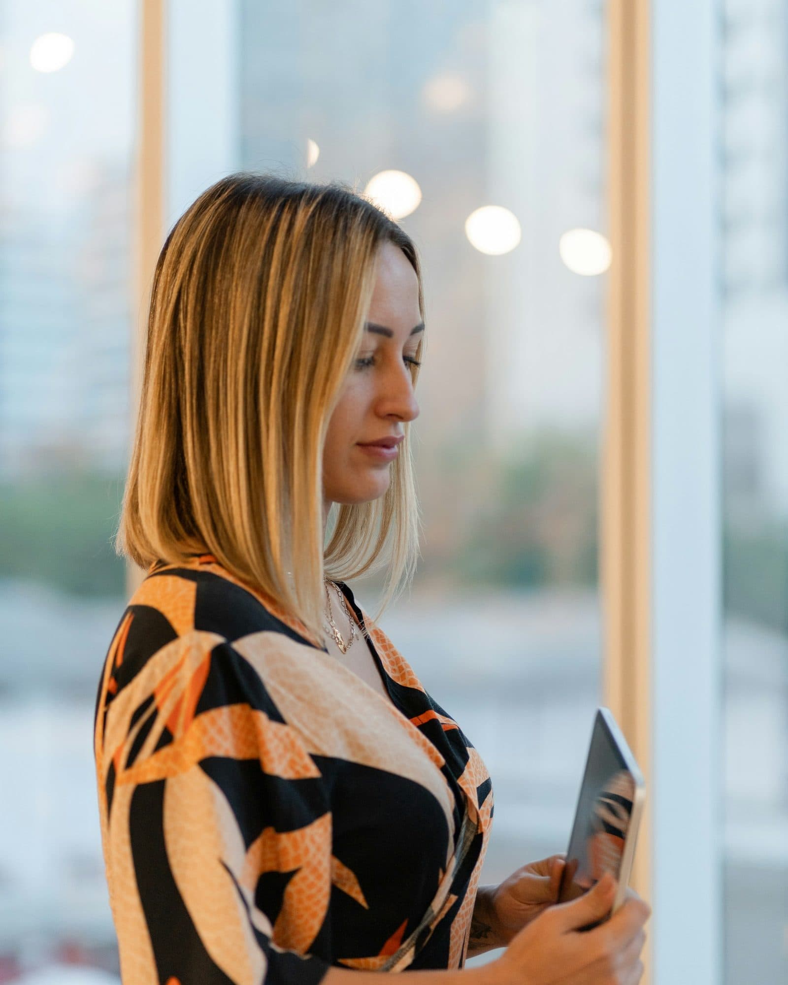 A professional reviews a plan on a tablet beside a window with city light