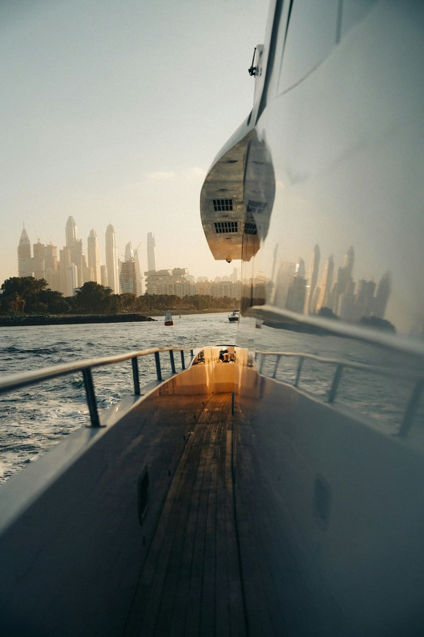 View along a yacht's side deck towards the Dubai skyline at sunset