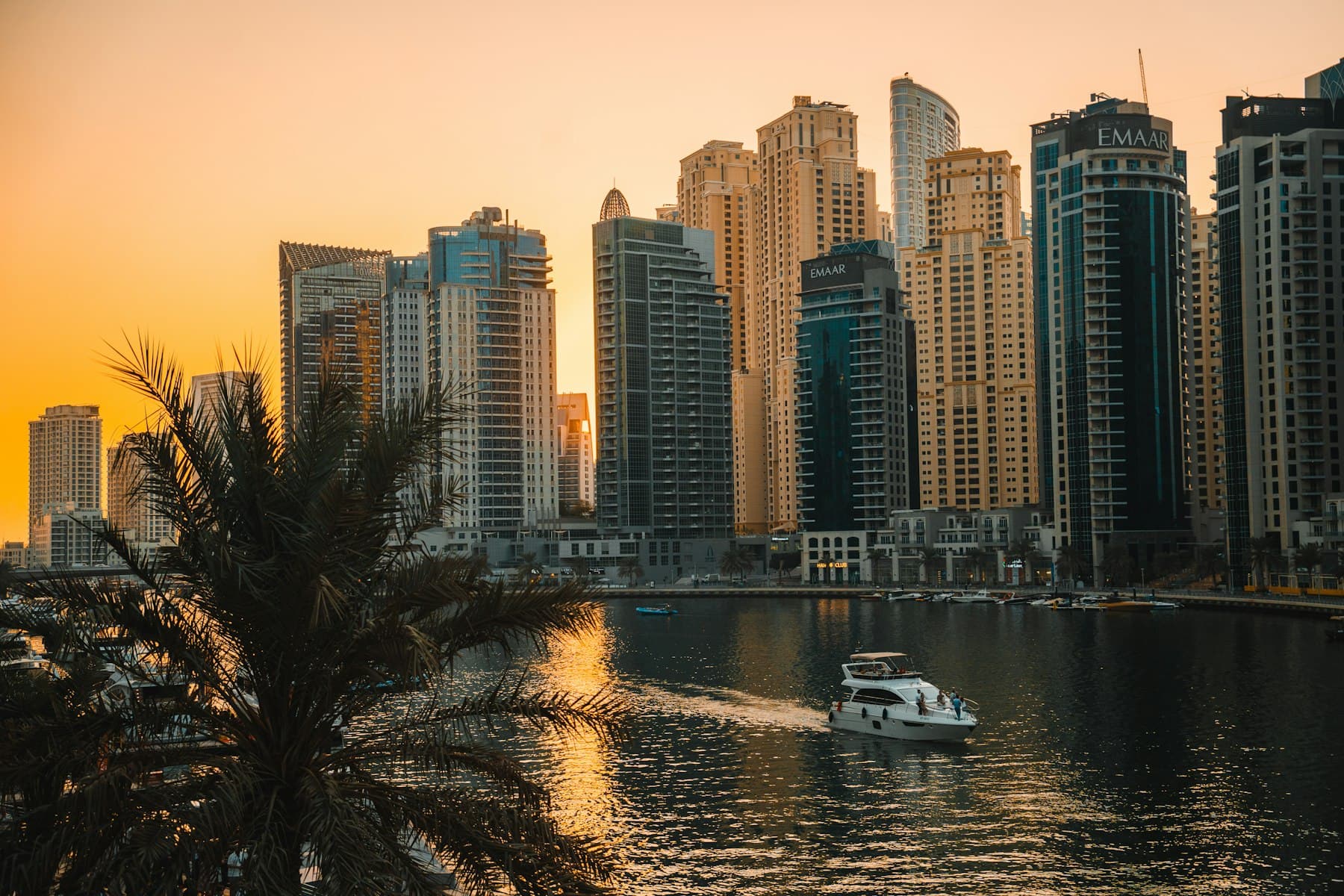 A boat crossing Dubai Marina at golden hour beneath the towers
